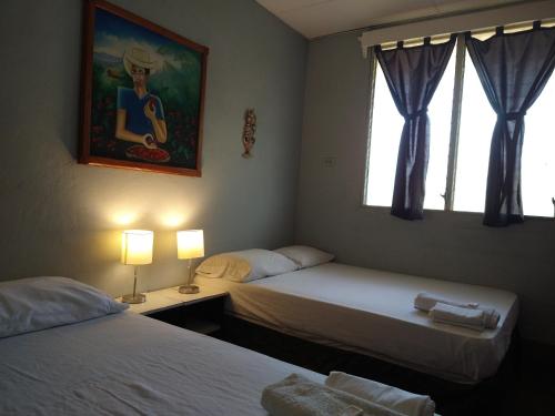 a bedroom with two beds and a painting on the wall at Hostal Harvest House in León
