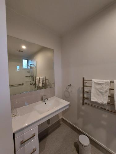 a white bathroom with a sink and a mirror at Elmore Lodge Motel in Hastings