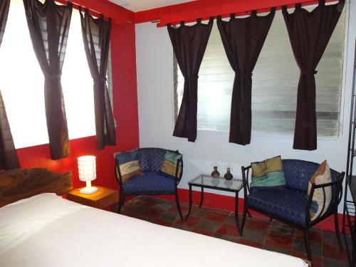 a bedroom with two chairs and a bed and windows at Hostal Harvest House in León
