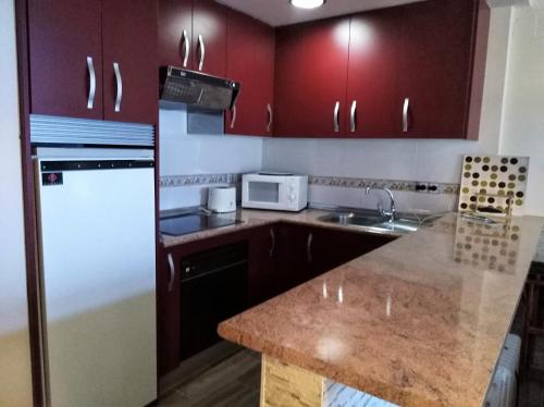 una cucina con armadi rossi e frigorifero bianco di AMÉRICA ELITE a Sierra Nevada