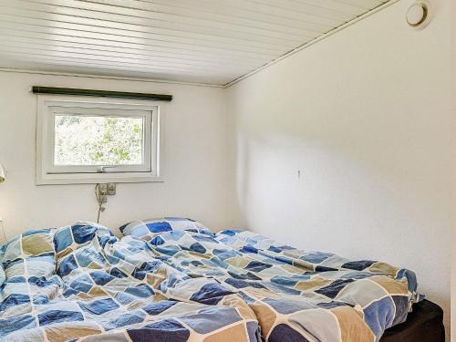 ein unverbautes Bett in einem Schlafzimmer mit einem Fenster in der Unterkunft Holiday home Væggerløse CCXIV in Bøtø By