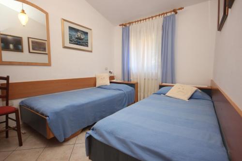 une chambre d'hôtel avec deux lits et une chaise dans l'établissement Apartments by the sea Novigrad - 7335, à Novigrad