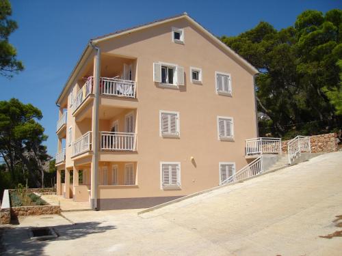 a large yellow building with white windows and balconies at Apartment Sveta Nedilja 14086a in Jelsa