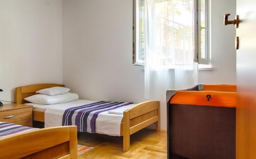 2 Betten in einem Zimmer mit einem Fenster und einem TV in der Unterkunft Apartment Sveta Nedilja 14086a in Jelsa