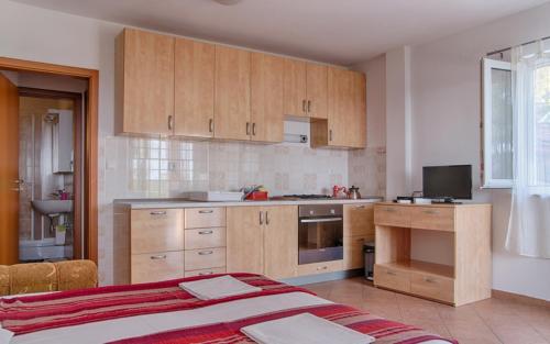 eine Küche mit Holzschränken und ein Bett in einem Zimmer in der Unterkunft Apartment Sveta Nedilja 14086a in Jelsa