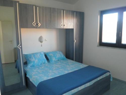 a bedroom with a bed with blue sheets and a mirror at Apartments with a parking space Lopar, Rab - 14089 in Lopar