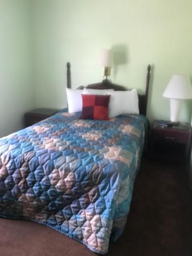 a bedroom with a bed with a colorful quilt on it at Itascan Motel in Grand Rapids