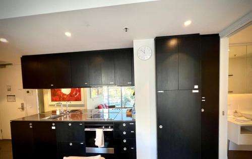 une cuisine avec des armoires noires et une horloge murale dans l'établissement Luxury 2 Bedroom Suite near Adelaide with a car park, à Broadview