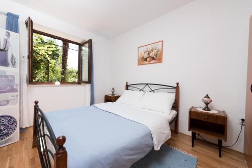 a bedroom with a white bed and a window at Apartments with a parking space Icici, Opatija - 14155 in Ičići
