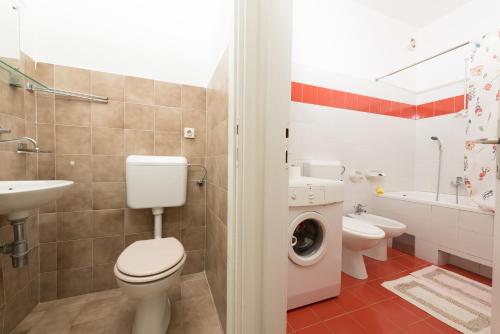 a bathroom with a toilet and a sink and a washing machine at Apartments with a parking space Icici, Opatija - 14155 in Ičići