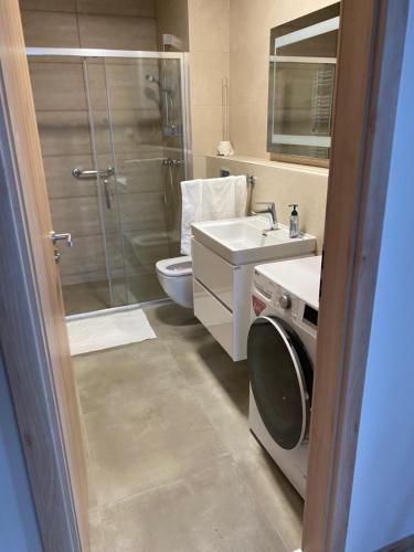 een badkamer met een douche, een wastafel en een wasmachine bij Apartman X12, Hillside in Dolný Kubín