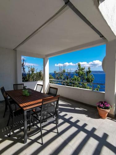 a patio with a wooden table and chairs and the ocean at Apartments by the sea Mimice, Omis - 14230 in Mimice