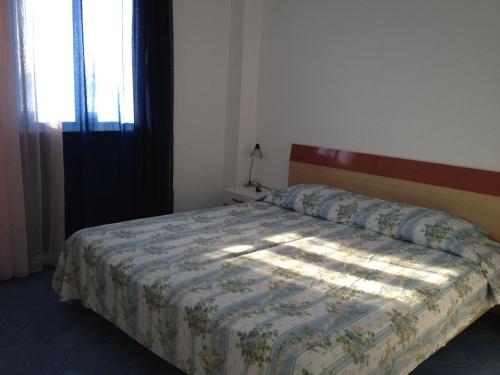 1 dormitorio con cama con edredón y ventana en Family friendly apartments with a swimming pool Razanj, Rogoznica - 14232 en Rogoznica