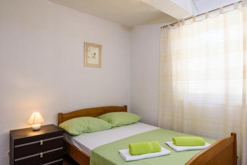 Schlafzimmer mit einem Bett mit grüner Bettwäsche und einem Fenster in der Unterkunft Apartments with a parking space Marina, Trogir - 14258 in Marina