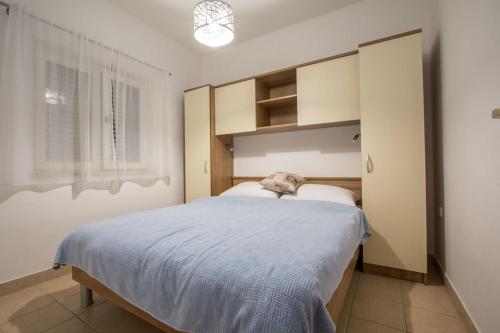 a bedroom with a bed with a blue blanket on it at Family friendly apartments with a swimming pool Verunic, Dugi otok - 14286 in Veli Rat