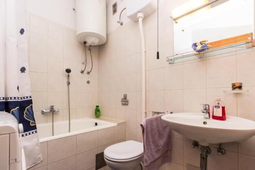 a bathroom with a sink and a toilet and a bath tub at Apartments with a parking space Omis - 14290 in Omiš