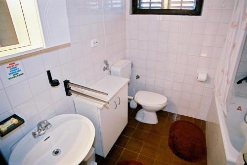 Baño blanco con aseo y lavamanos en Seaside holiday house Ist - 14366, en Ist