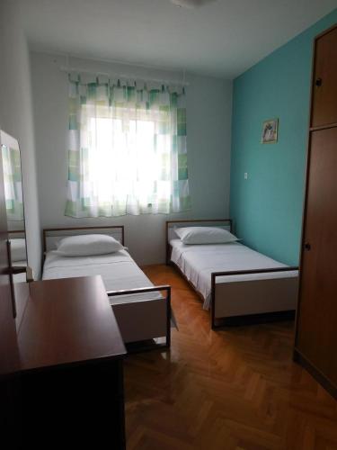 a room with two beds and a table and a window at Apartments by the sea Povlja, Brac - 14367 in Povlja