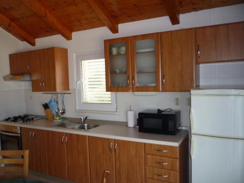 a kitchen with wooden cabinets and a white refrigerator at Apartments with a parking space Savar, Dugi otok - 14373 in Savar