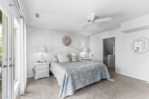 a white bedroom with a bed and a ceiling fan at 5280 Waves in Corolla