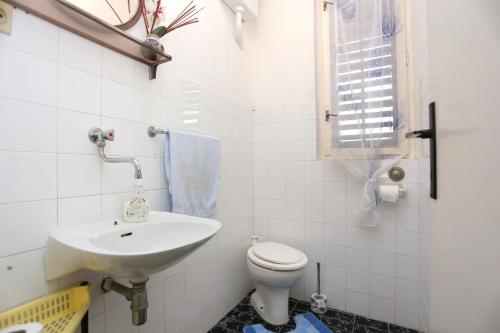 Baño blanco con lavabo y aseo en Apartments by the sea Sumpetar, Omis - 14450 en Jesenice