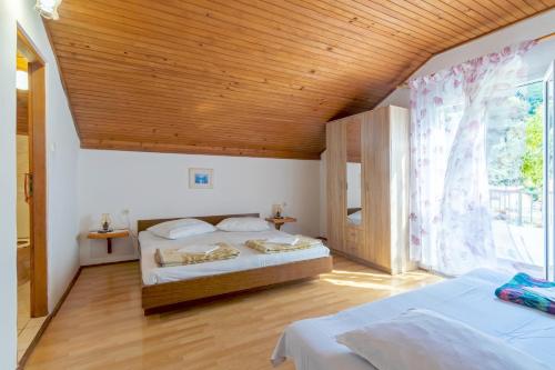 1 Schlafzimmer mit 2 Betten und Holzdecke in der Unterkunft Apartments by the sea Cove Vela Stiniva, Hvar - 14511 in Zastražišće