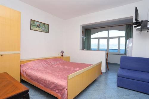 a bedroom with a bed and a window and a blue chair at Apartments by the sea Slatine, Ciovo - 14541 in Slatine