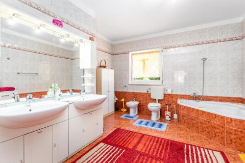 La salle de bains est pourvue de 2 lavabos, d'une baignoire et de toilettes. dans l'établissement Family friendly apartments with a swimming pool Rijeka - 14294, à Rijeka