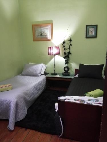 a bedroom with two beds and a table with a lamp at Casa dragão in Porto