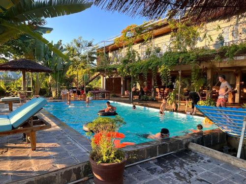un gruppo di persone in piscina presso un resort di Jungle Boss Travel Lodge a Phong Nha