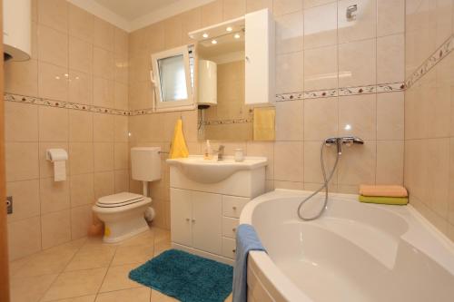 a bathroom with a tub and a toilet and a sink at Apartments by the sea Slatine, Ciovo - 16341 in Slatine
