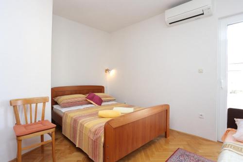 a bedroom with a bed and a chair in it at Apartments by the sea Slatine, Ciovo - 16341 in Slatine