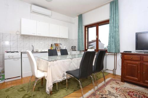una cucina con tavolo, sedie e televisore di Apartments with a parking space Kastel Stari, Kastela - 16344 a Kaštela (Castelli)