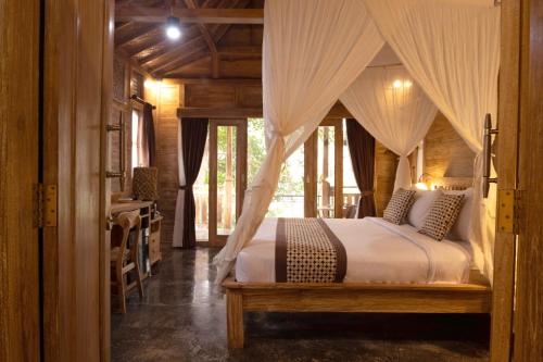 - une chambre avec un lit à baldaquin dans l'établissement Homayoon Private Villa Ubud, à Ubud