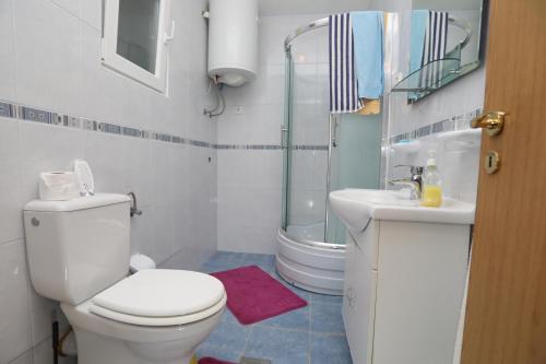 a white bathroom with a toilet and a sink at Apartment Vinisce 16439b in Vinišće