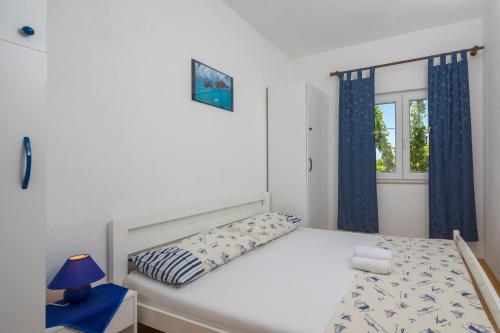 1 dormitorio con 1 cama con cortinas azules y ventana en Holiday house with a swimming pool Rogac, Solta - 16444 en Grohote