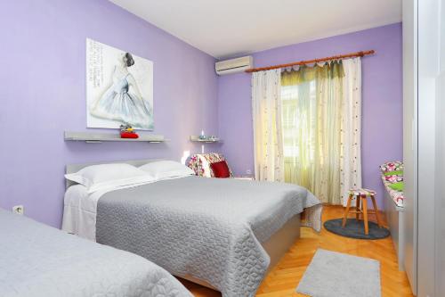 1 Schlafzimmer mit 2 Betten und lila Wänden in der Unterkunft Apartments by the sea Podgora, Makarska - 16476 in Podgora