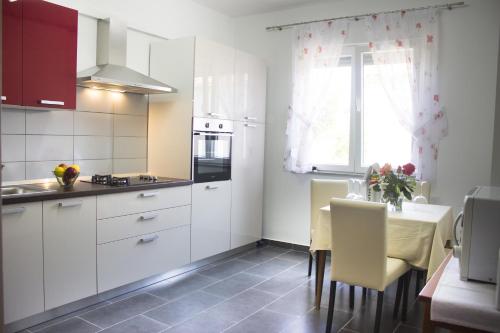 een keuken met witte kasten en een tafel met stoelen bij Apartments with a parking space Sutomiscica, Ugljan - 16524 in Preko