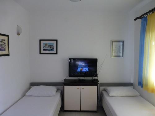 a room with two beds and a tv in it at Apartment Mali Iz 16535b in Veli Iž