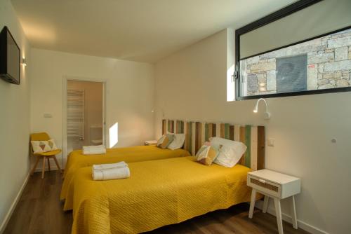 a bedroom with two beds with yellow sheets and a window at Varanda de Sistelo in Sistelo