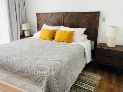 a bedroom with a large bed with two yellow pillows at Alta Vista Las Condes in Santiago