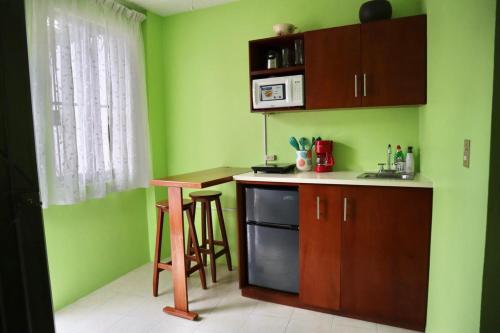 a kitchen with green walls and a counter and a table at Casa Margarita Oaxaca in Oaxaca City