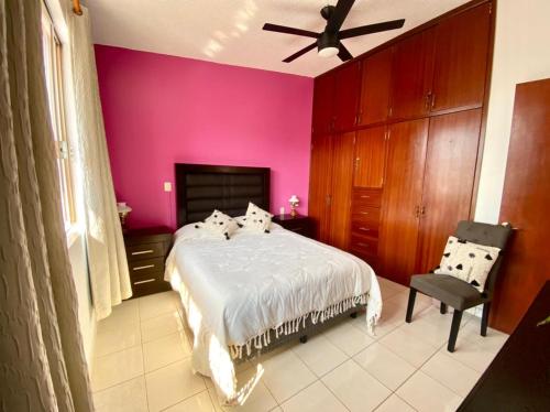a bedroom with a bed and a pink wall at Casa Margarita Oaxaca in Oaxaca City