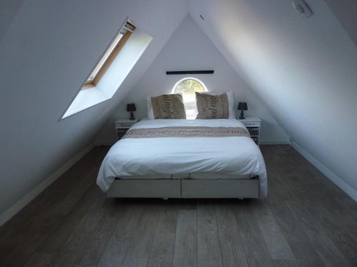 a bedroom with a bed in a attic with a window at Schiphol Apartments in Aalsmeer