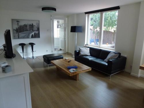 a living room with a black couch and a coffee table at Schiphol Apartments in Aalsmeer