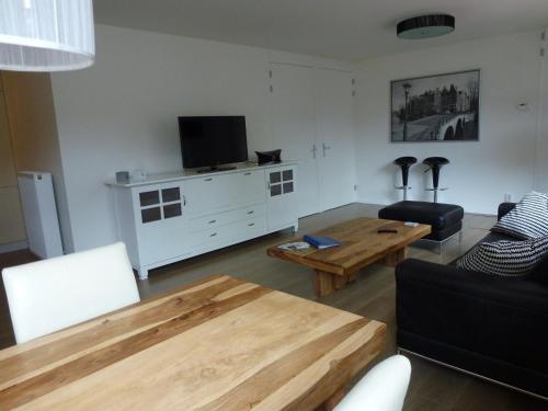 a living room with a table and a tv at Schiphol Apartments in Aalsmeer