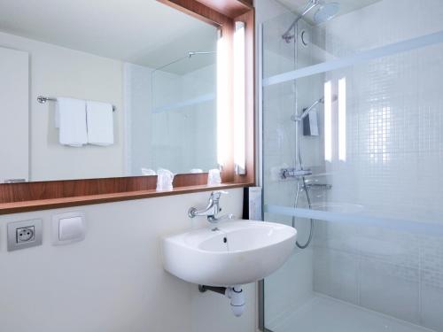 een witte badkamer met een wastafel en een douche bij Campanile Villejuif in Villejuif