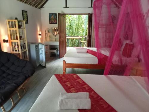 a bedroom with two beds with pink curtains and a desk at Nary Garden in Kampot