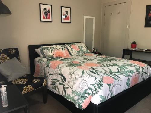 um quarto com uma cama com um edredão floral em L'École Private Studio-Apartment by My Lodgingfy em Moorabbin