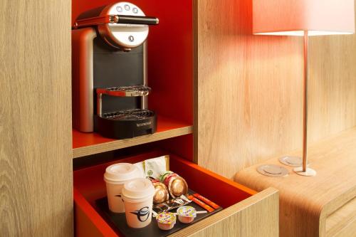 a cupboard with coffee and pastries and drinks in a room at Oceania Paris Roissy CDG in Le Mesnil-Amelot